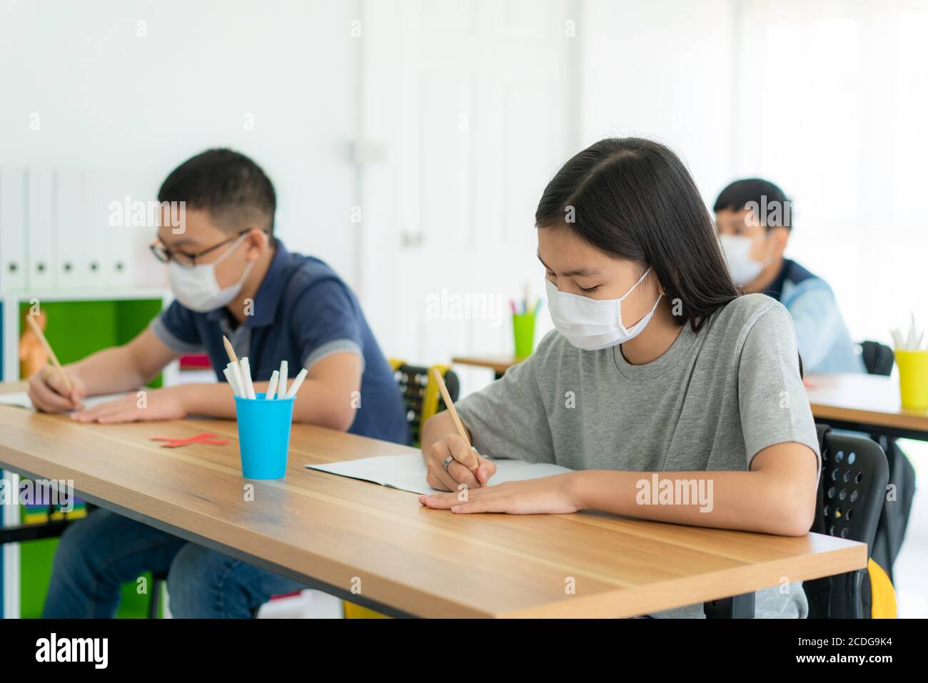 Gruppe von asiatischen Grundschüler tragen hygienische Maske im Klassenzimmer und lächeln glücklich zu sein, während zurück zur Schule wieder ihre Schule, New NOR Stockfoto