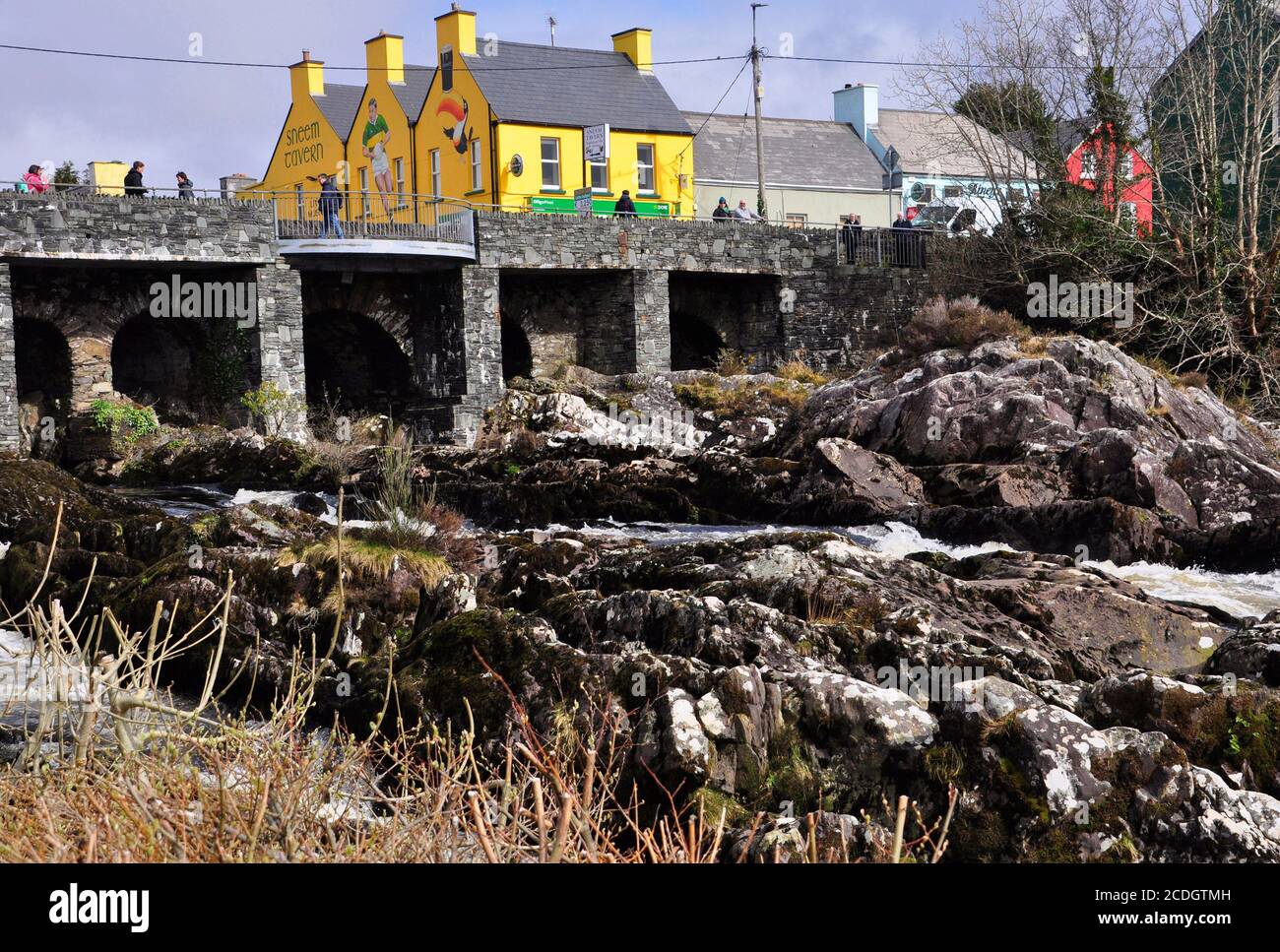 Hell bemalte Taverne im Dorf Sneem mit dem Wasserfall auf dem Fluss Sneem im Vordergrund. Iveragh Halbinsel, Grafschaft Kerry in Irland Stockfoto