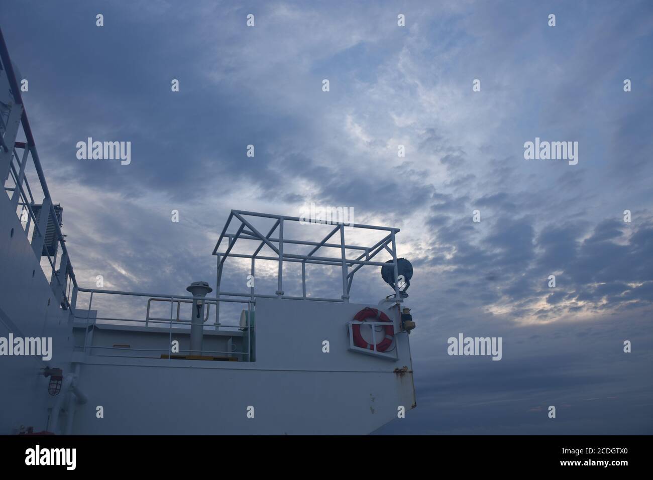 Steuerbord Seitenflügel der Navigationsbrücke des Frachtschiffes mit dem orangefarbenen Rettungsring, Gyro-Kompass-Repeater, Suchlicht und Metallrahmen. Stockfoto
