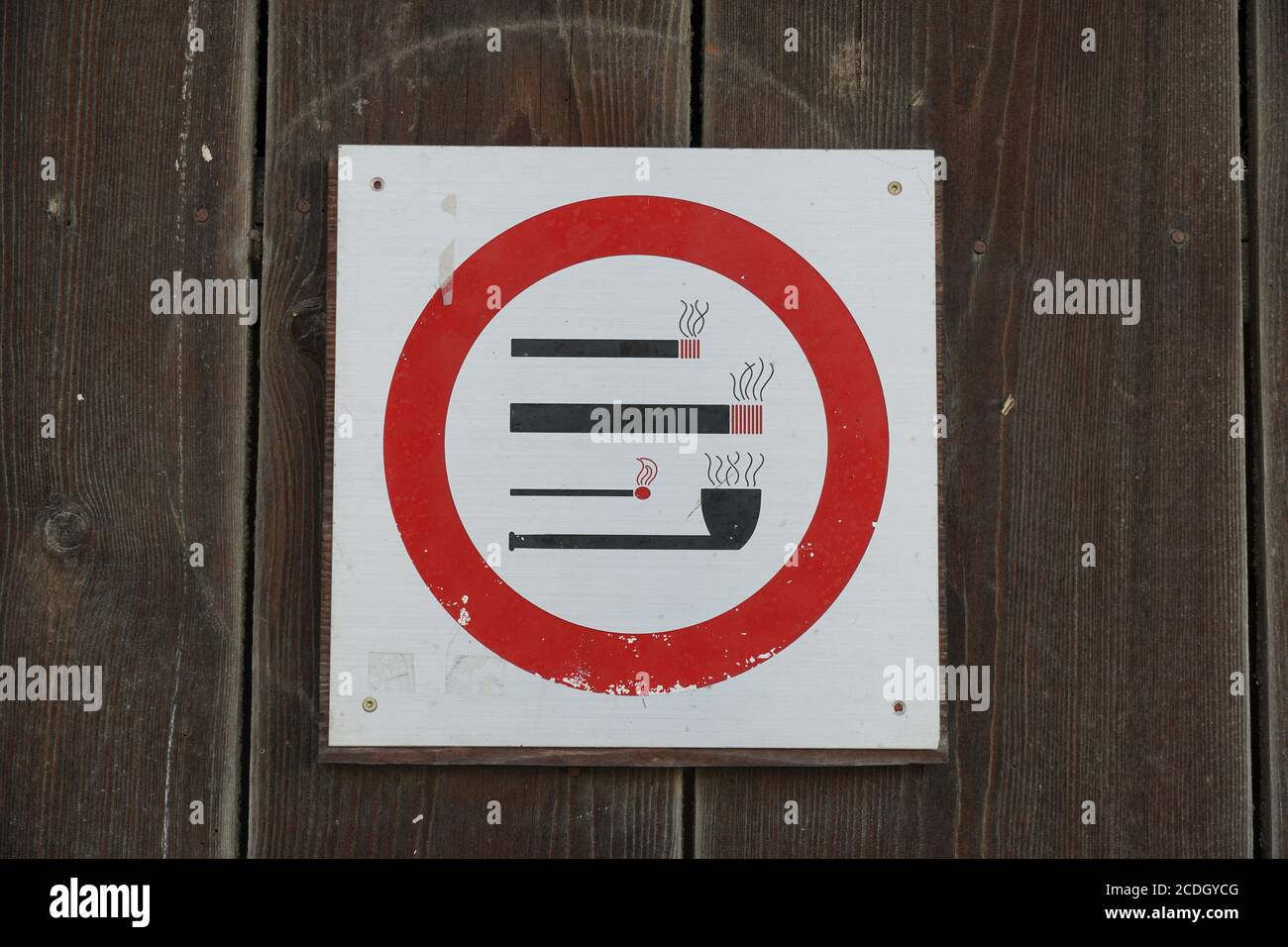 Ein Schild auf einem hölzernen Tor, das das Rauchen verbietet. Das Verbot betrifft alle Arten von Tabakerzeugnissen, die eine Entzündung des Feuers benötigen. Es sind Zigaretten. Stockfoto