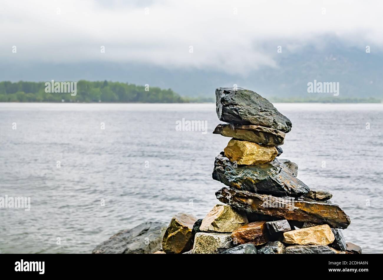 Verschiedene Steine übereinander in der gestapelt Form einer Pyramide liegen am Ufer des see in nebligen regnerischen Wetter Stockfoto