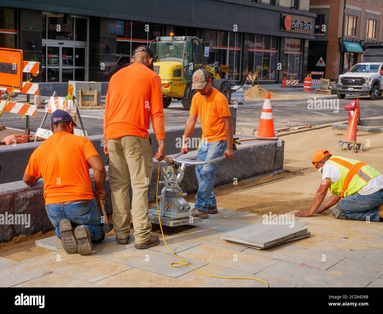 Bauarbeiter mit elektrischen Saugheber, um Straßenpflaster auf Lake Street Reconstruction Project zu platzieren. Oak Park, Illinois. Stockfoto