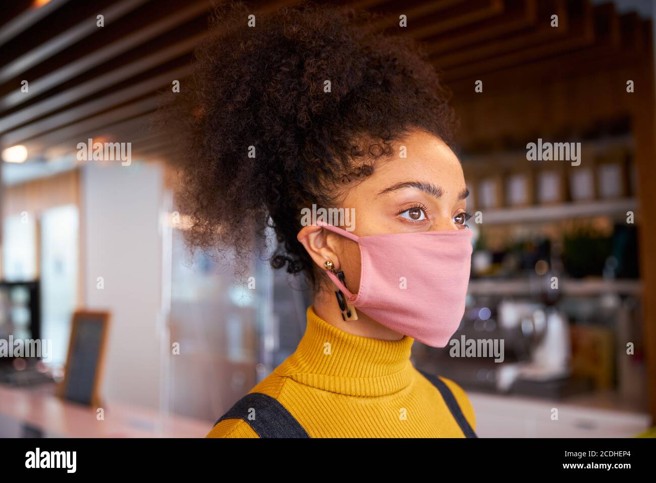 Weibliche afrikanische Café-Besitzer trägt Gesichtsmaske Blick aus der Kamera. Stockfoto