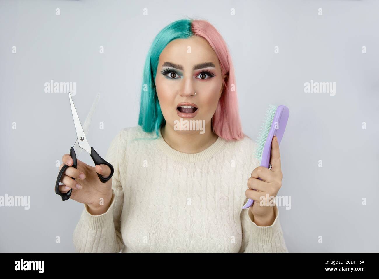 Verwirrt Frauen halten Schere in einer Hand und Haarbürste In einer anderen Hand Stockfoto