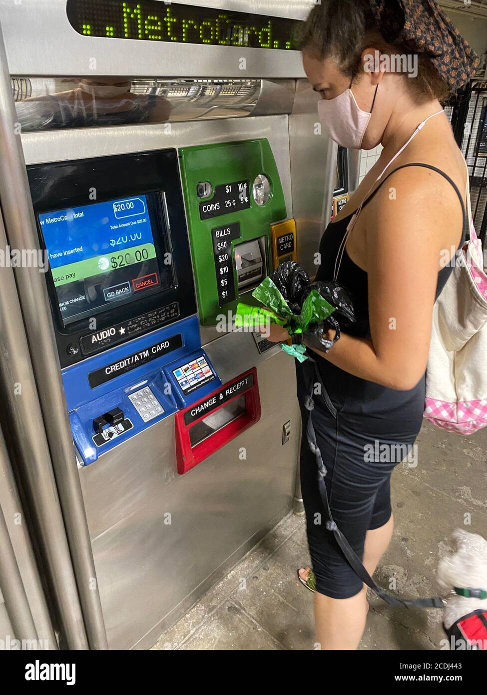 Frau mit Hund im Schlepptau füllt ihre MetroCard an der Fort Hamilton Parkway U-Bahnstation in Brooklyn, New York. Stockfoto