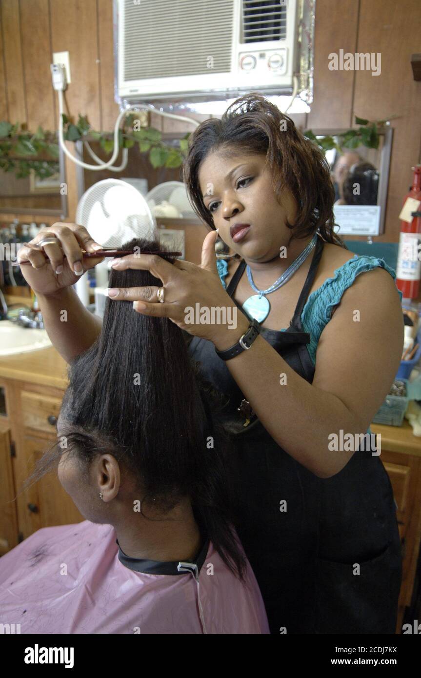 Pine Bluff, AR 17. Oktober 2006: Afroamerikanische Kleinunternehmerin arbeitet in ihrem Laden in der Nähe des Campus der Community College an den Haaren einer Kundin, wo sie eine Ausbildung zur Eröffnung ihres eigenen Friseurgeschäfts erhielt. Modellversionen verfügbar. ©Bob Daemmrich Stockfoto