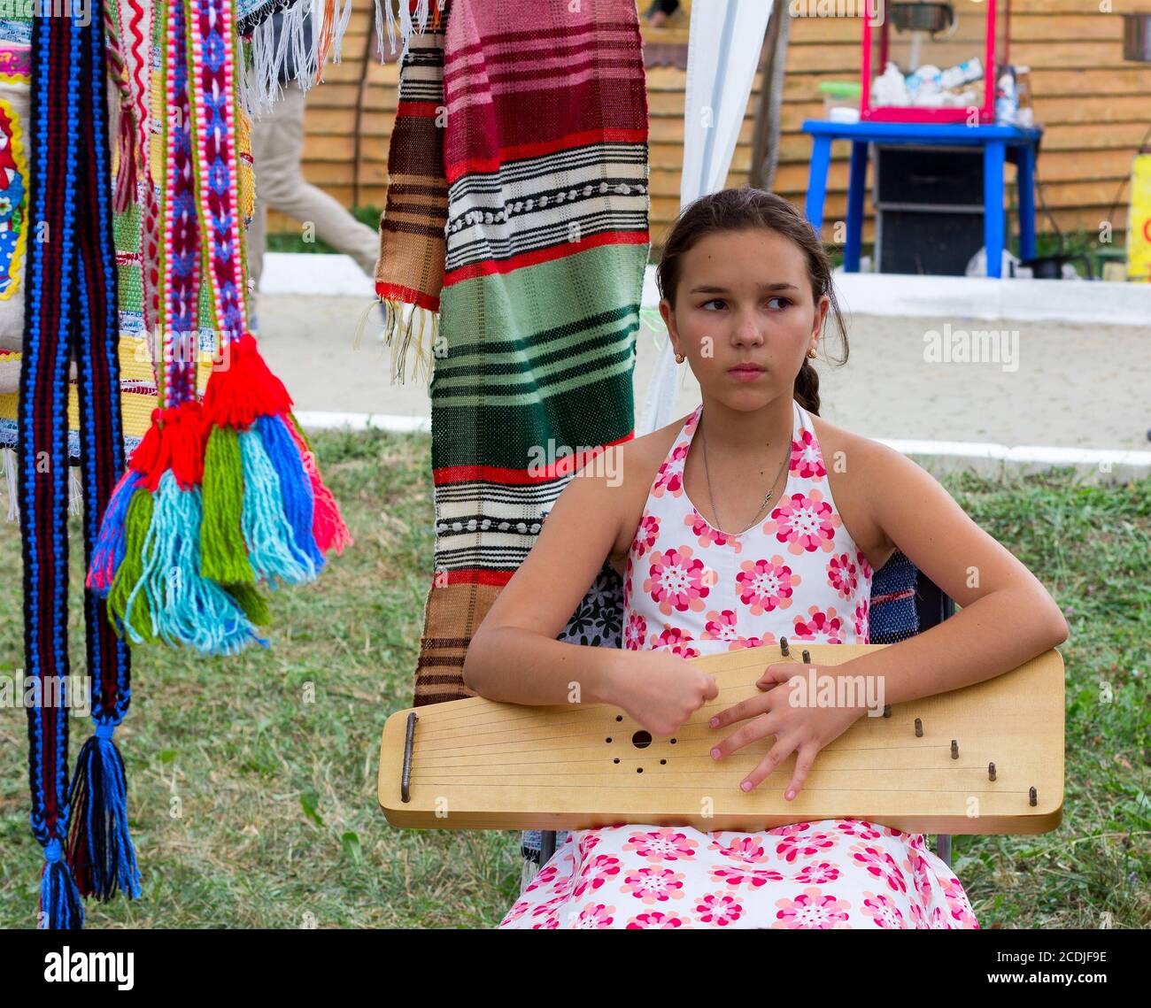 Adygea, Russland - 19. August 2017: Trauriges Mädchen, das auf der Harfe beim Festival von Käse Adyghe in Adygea Musik spielt Stockfoto