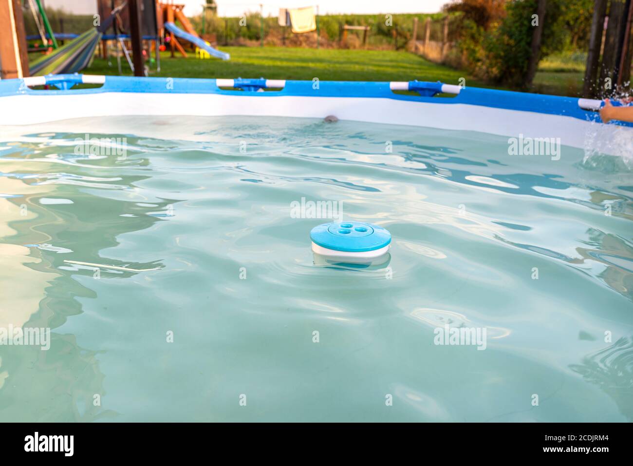 Blauer Chlorspender schwimmt in einem Haus Pool im Garten, Reinigung und Pflege des heimischen Pools. Stockfoto