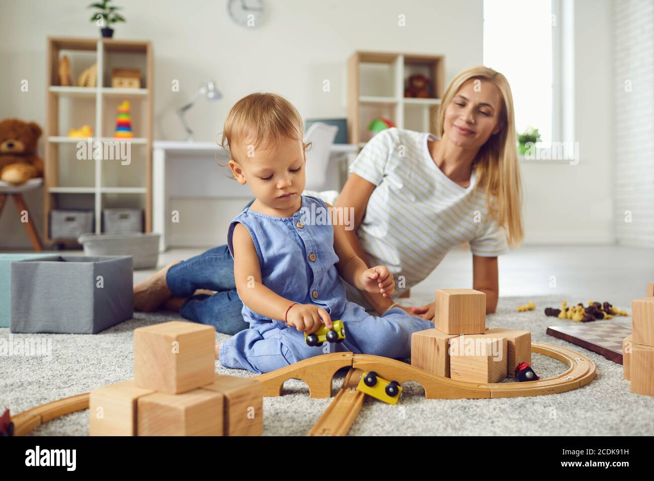 Junge Babysitter und kleines Kind spielen mit Holzklötzen in Gemütlicher Kinderzimmer Stockfoto