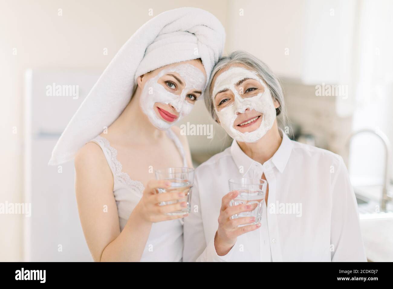 Beauty, Hautpflege und gesundes Lifestyle-Konzept. Innenaufnahme von zwei Frauen, Mutter und Tochter, entspannend mit Gesichtsmasken, posiert mit der Kamera Stockfoto