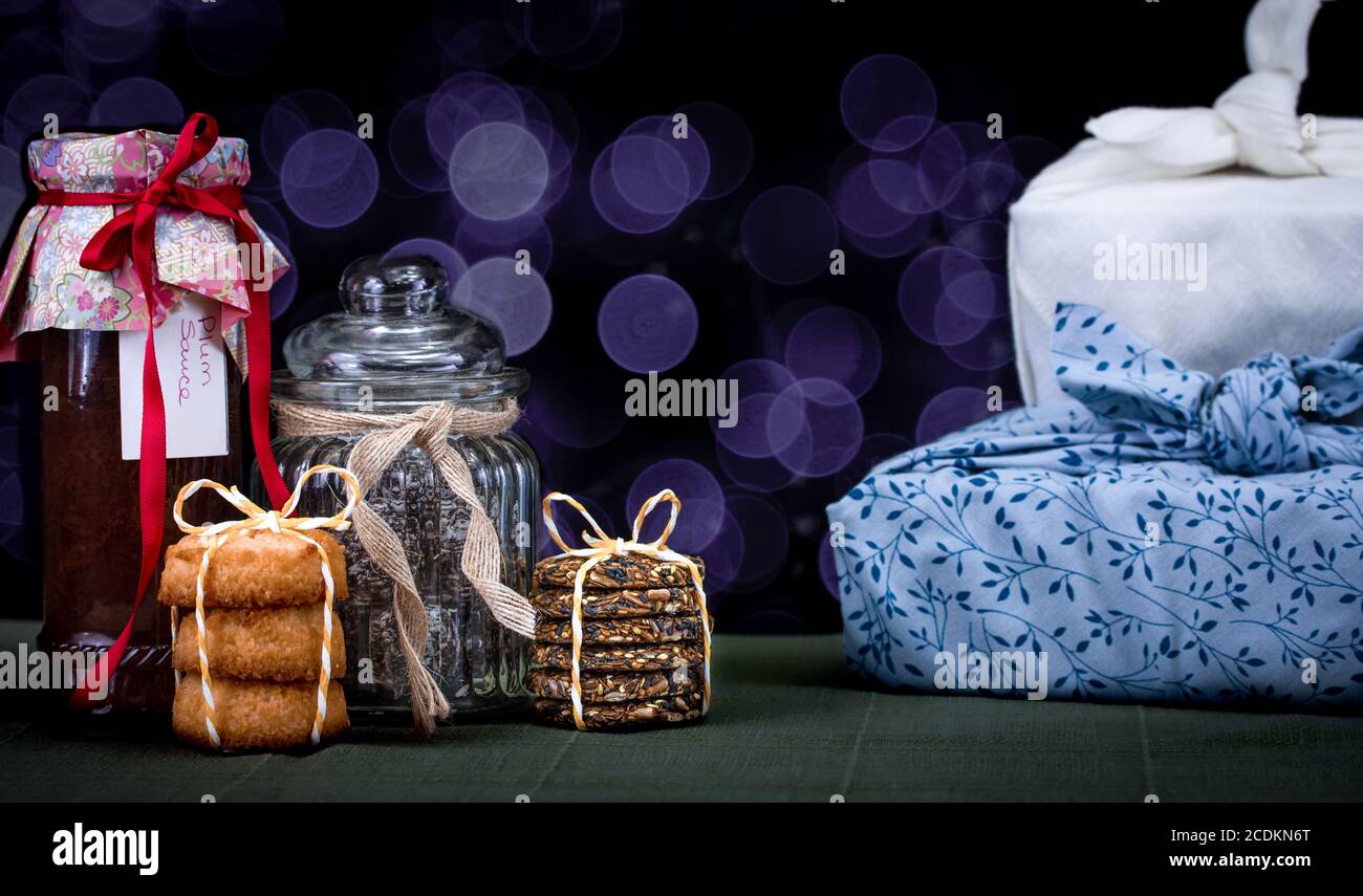 Authentische hausgemachte Marmeladen und Kekse mit Stoff Geschenk verpackt Geschenke. Machen, backen, recyceln und wiederverwenden für nachhaltiges Schenken für Feiertage, Feiern und Stockfoto