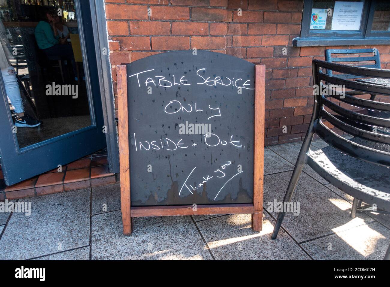 Ein Kreidetafel außerhalb eines Pubs in Exmouth, Devon, Großbritannien, informiert Kunden, dass Speisen und Getränke nur aufgrund von Coronaviren am Tisch erhältlich sind. Stockfoto