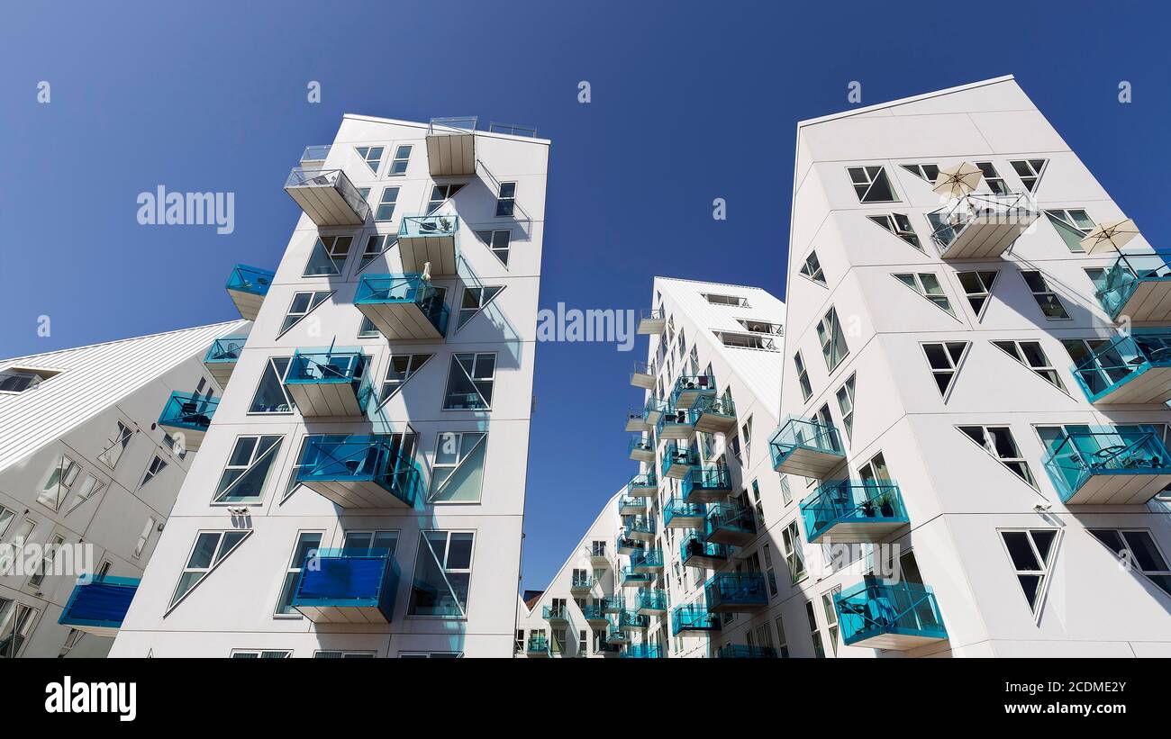 Weiße Wohnanlage mit türkisfarbenen Balkonen gegen einen blauen Himmel, zackige Gebäudeskulptur Isbjerget, Eisberg, moderne Architektur in der Stockfoto