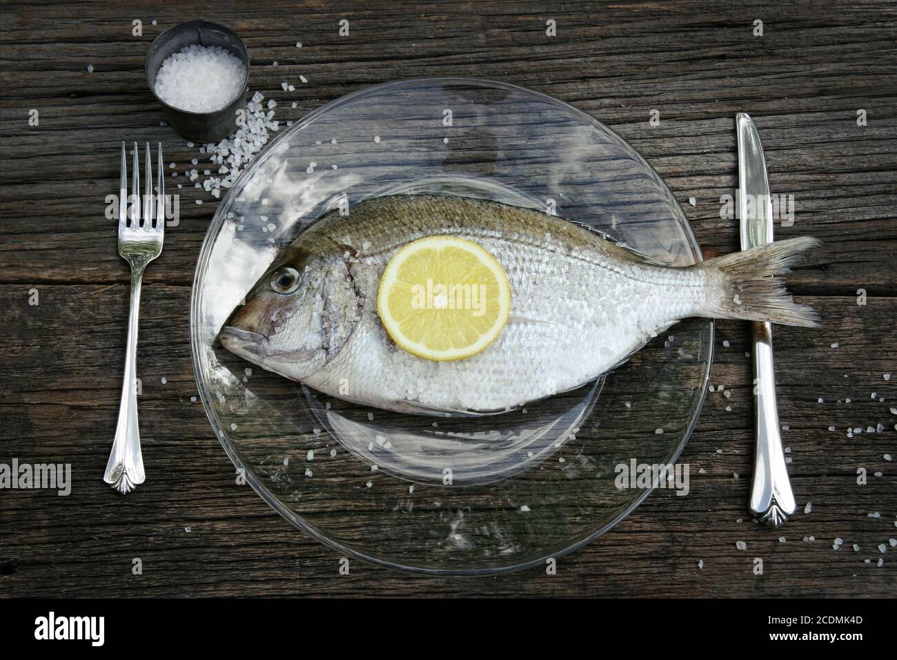 Roher Fisch auf Teller mit Messer und Gabel Stockfoto