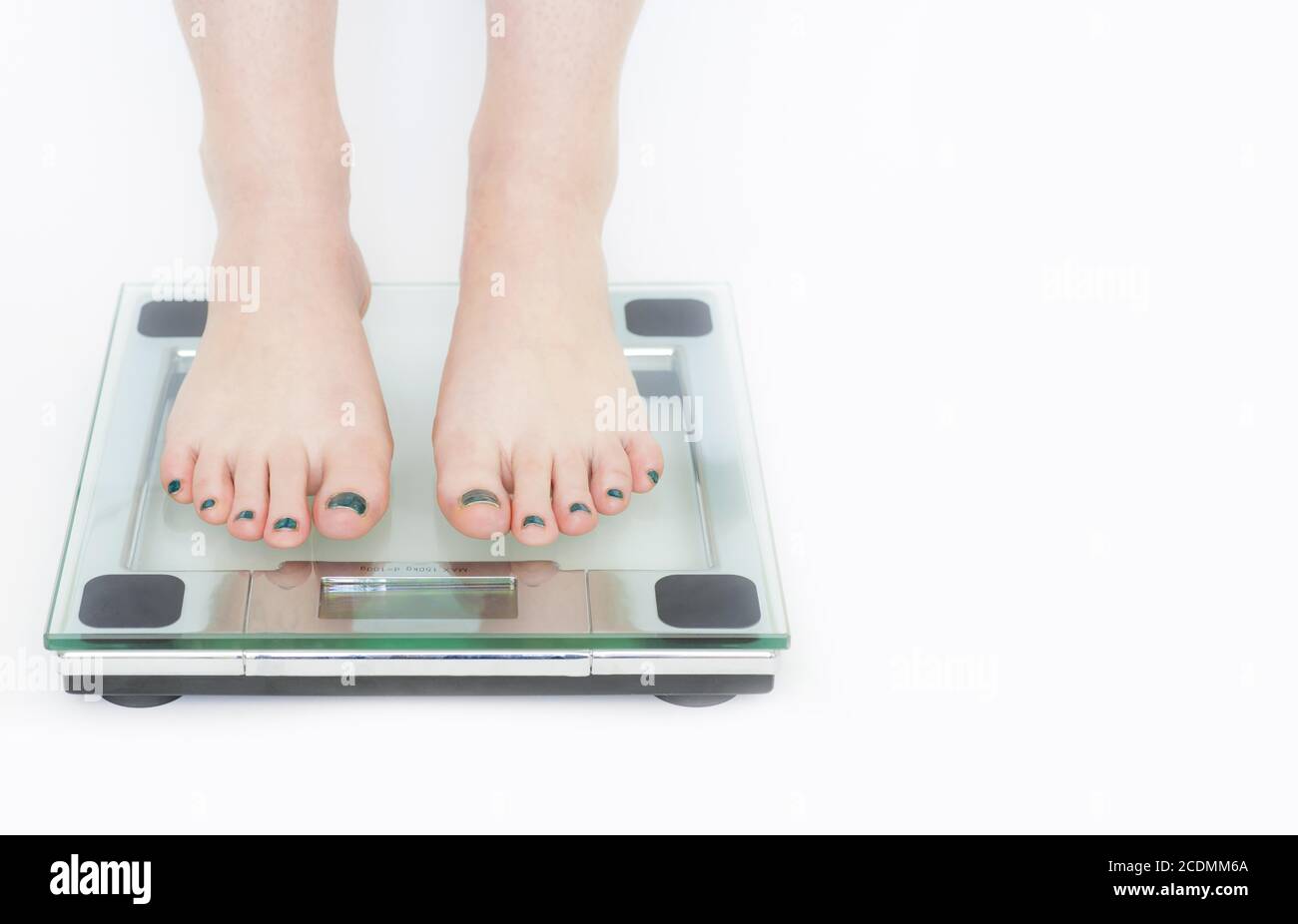 Frau in einer Wiegemaschine mit weißem Hintergrund, Gesundheits- und Gewichtskonzepte Stockfoto
