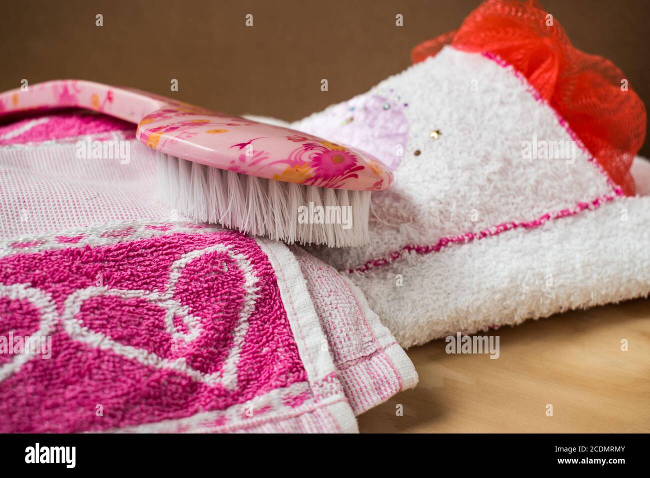 Rosa und weiße Handtücher mit einer Duschbürste auf einem Holztisch Stockfoto