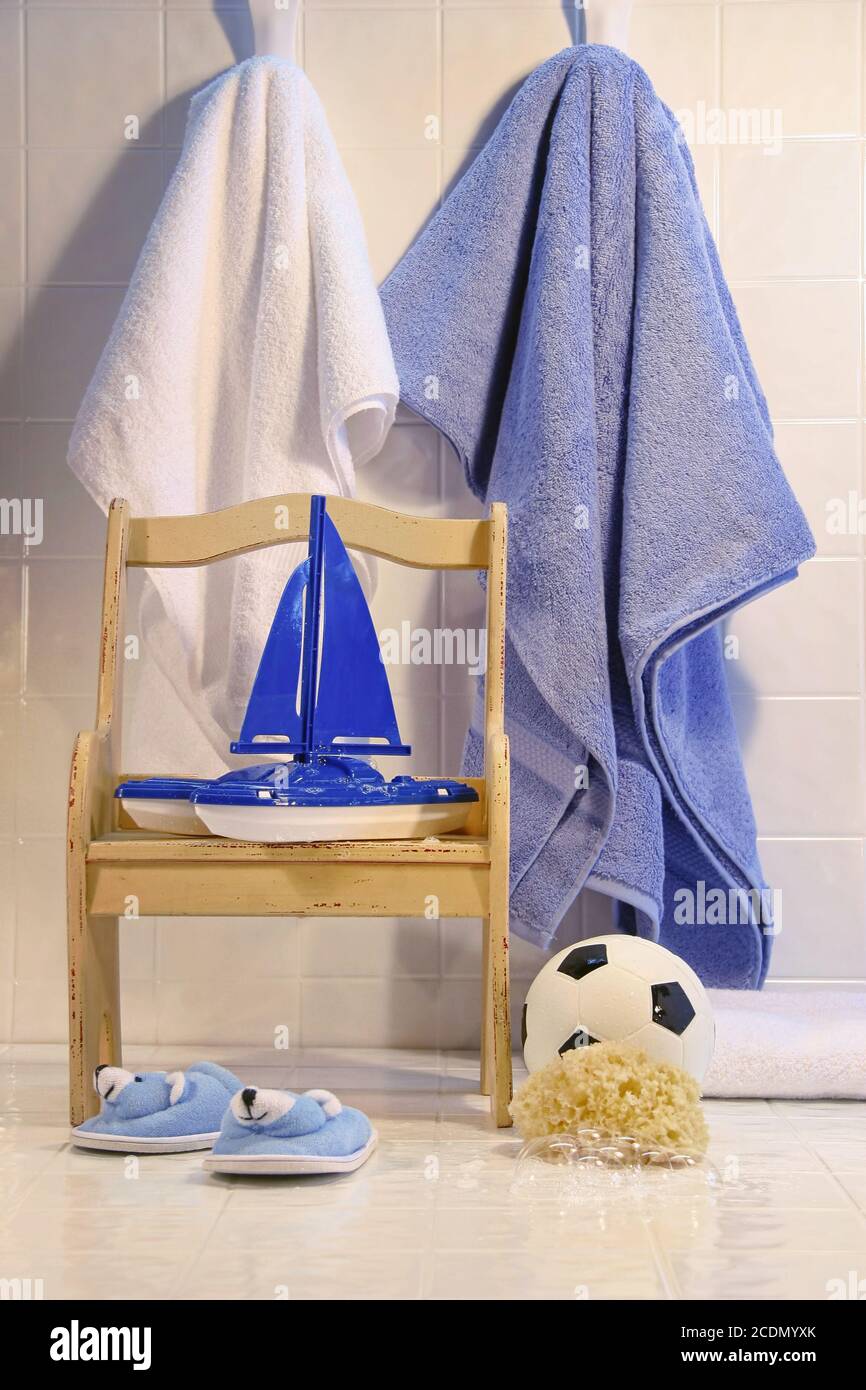 Spielzeug mit Stuhl und Handtücher auf dem Badezimmerboden Stockfoto