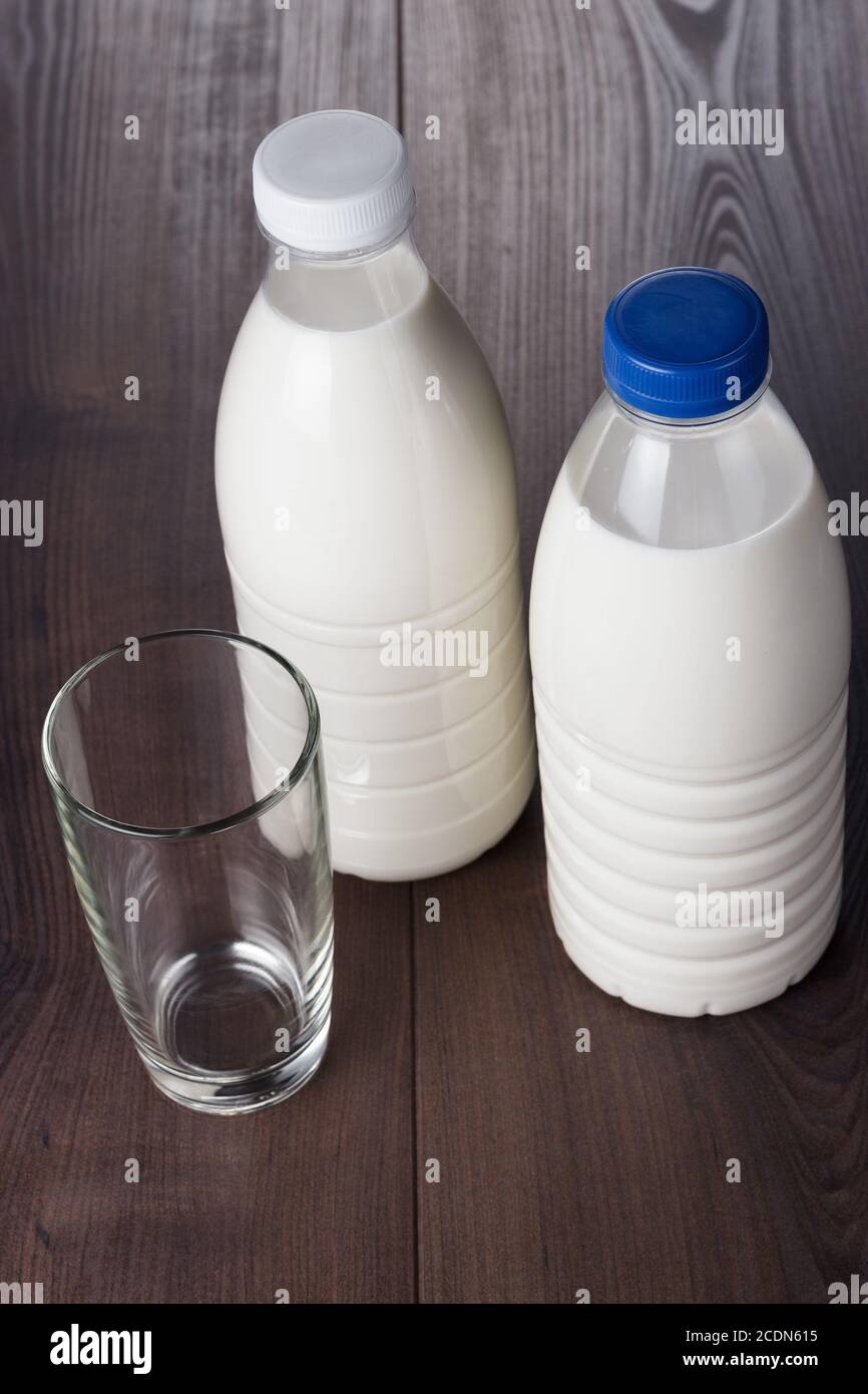 Leeres Glas und zwei Flaschen Milch Stockfoto