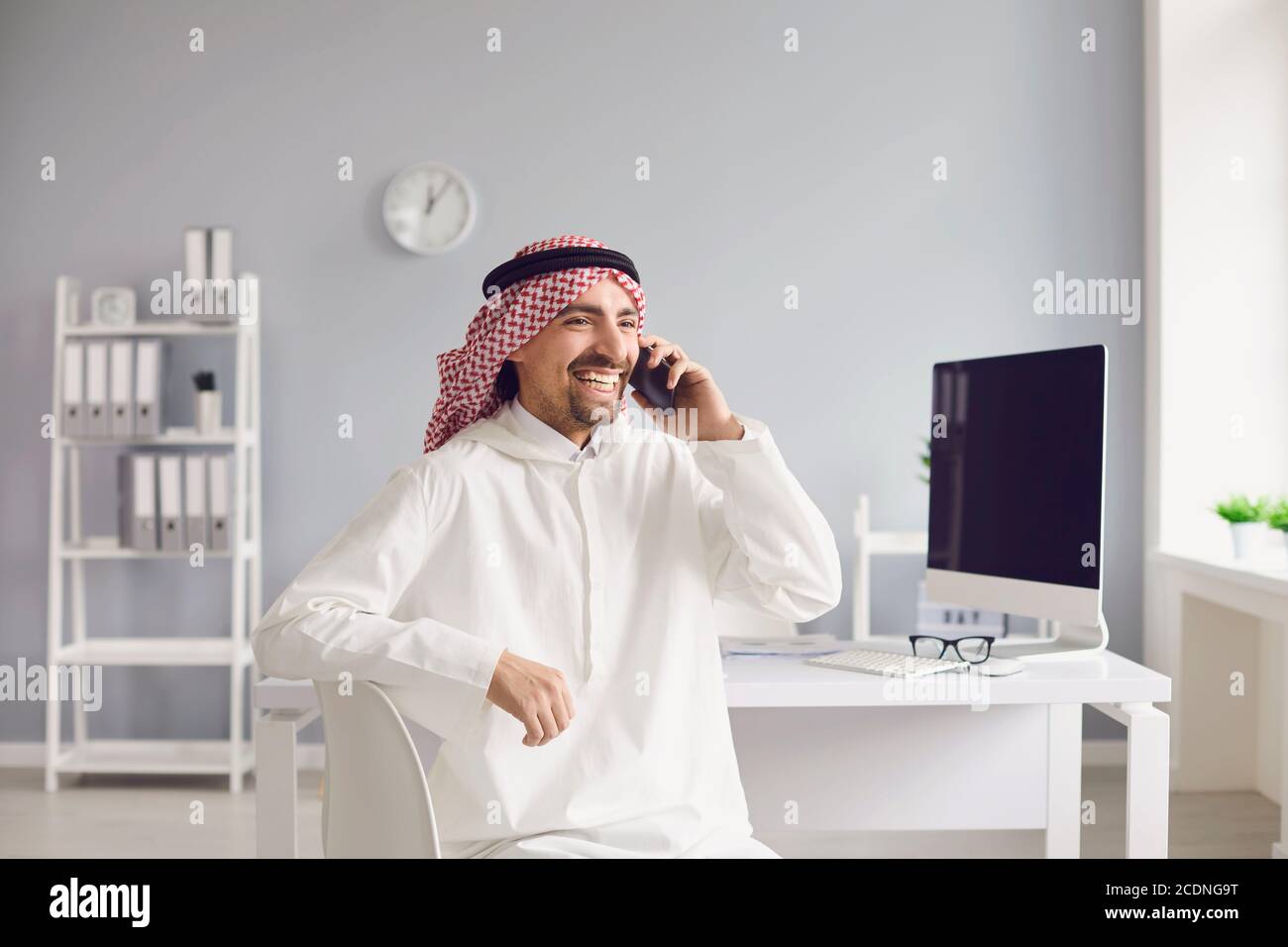 Arabischer Mann, der im Büro auf einem Handy spricht. Stockfoto