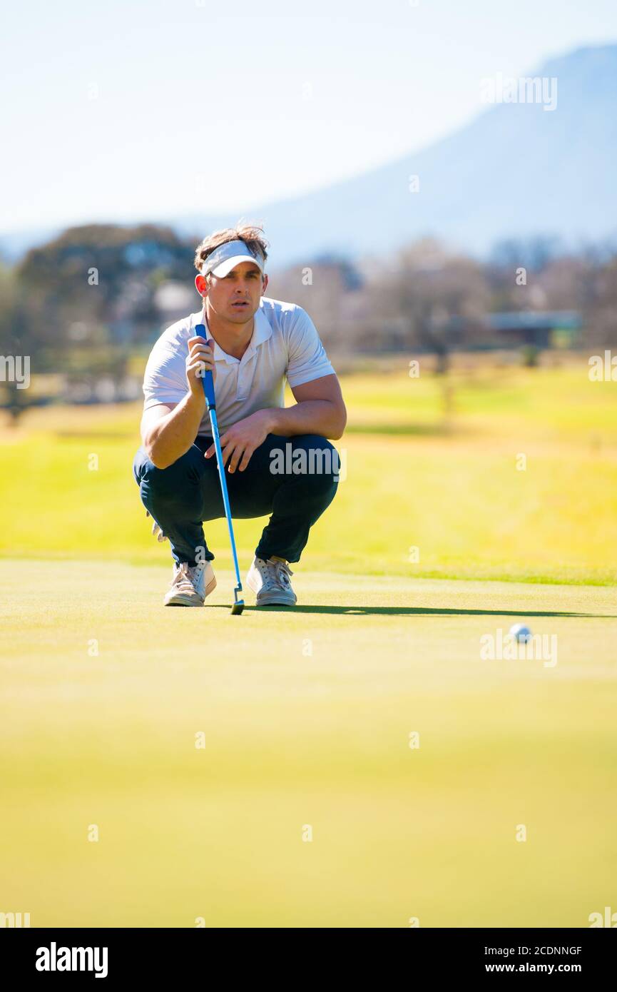 Mitte der zwanziger Jahre männlichen Golfer Planung seiner Putting Schuss auf die PIN auf einem Grün an einem hellen sonnigen Tag Stockfoto