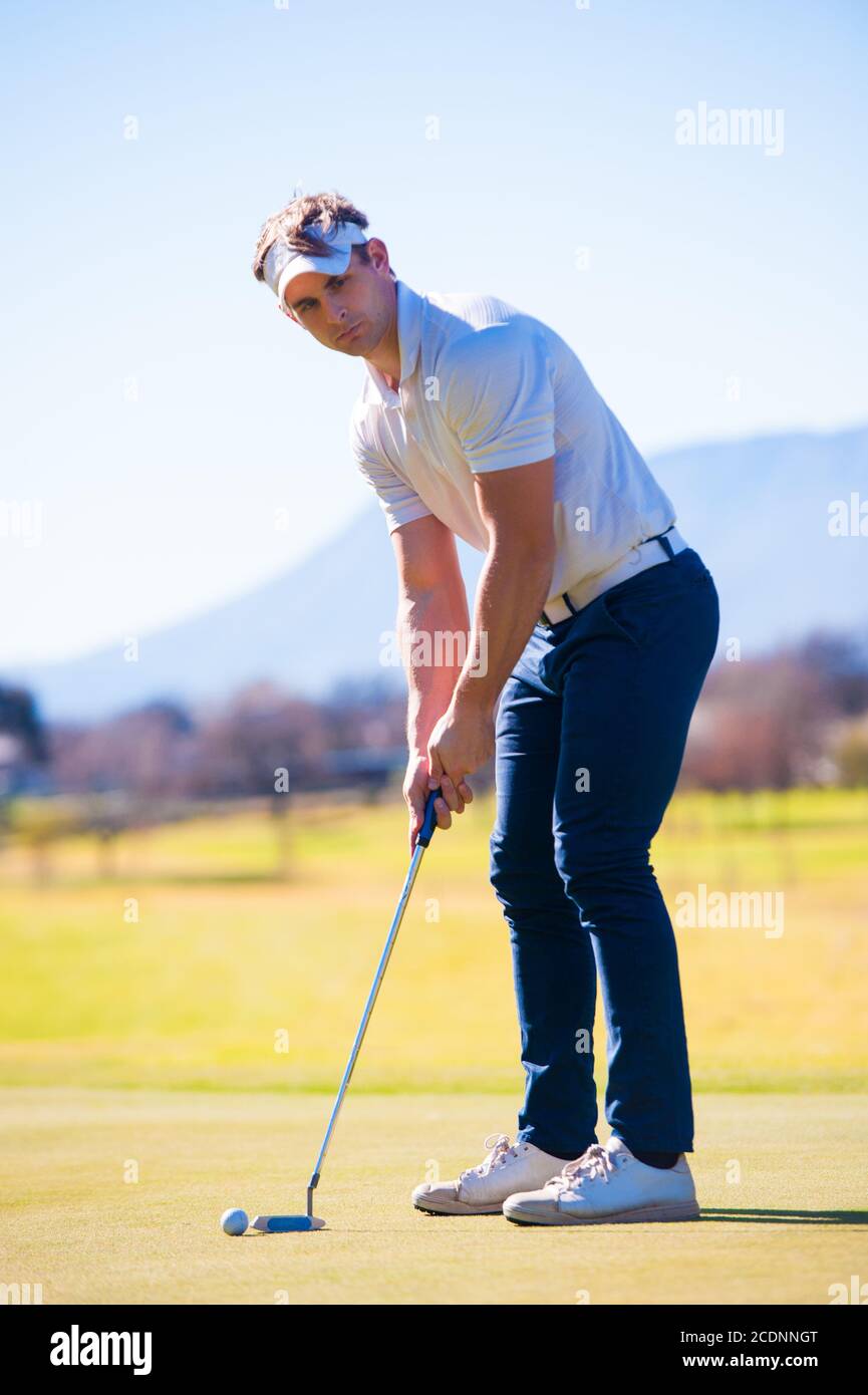 Mitte der zwanziger Jahre männlichen Golfer Planung seiner Putting Schuss auf die PIN auf einem Grün an einem hellen sonnigen Tag Stockfoto
