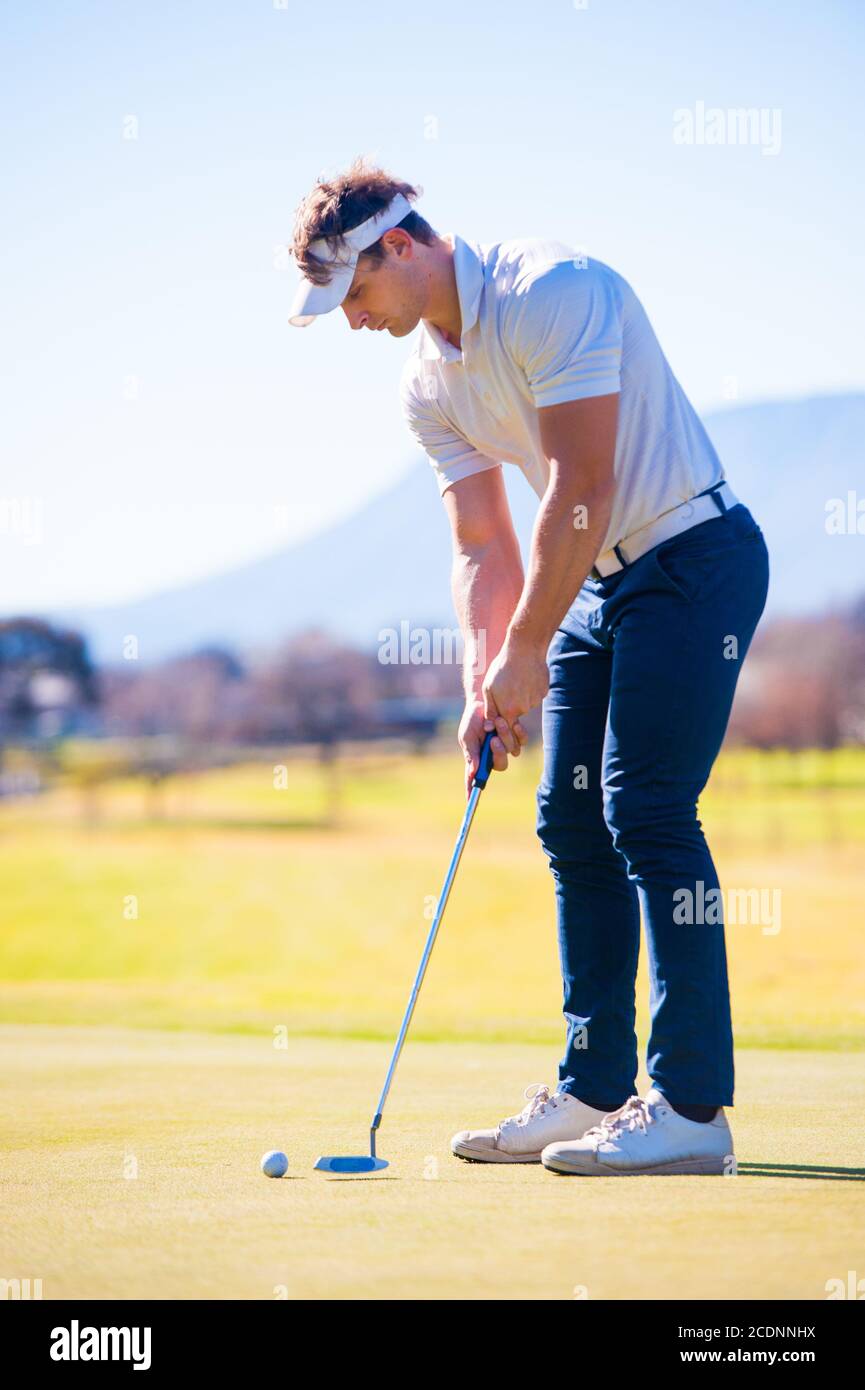 Mitte der zwanziger Jahre männlichen Golfer Planung seiner Putting Schuss auf die PIN auf einem Grün an einem hellen sonnigen Tag Stockfoto