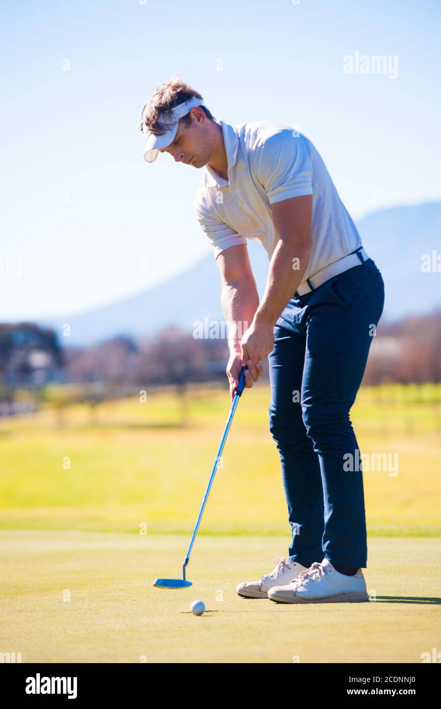 Mitte der zwanziger Jahre männlichen Golfer Planung seiner Putting Schuss auf die PIN auf einem Grün an einem hellen sonnigen Tag Stockfoto