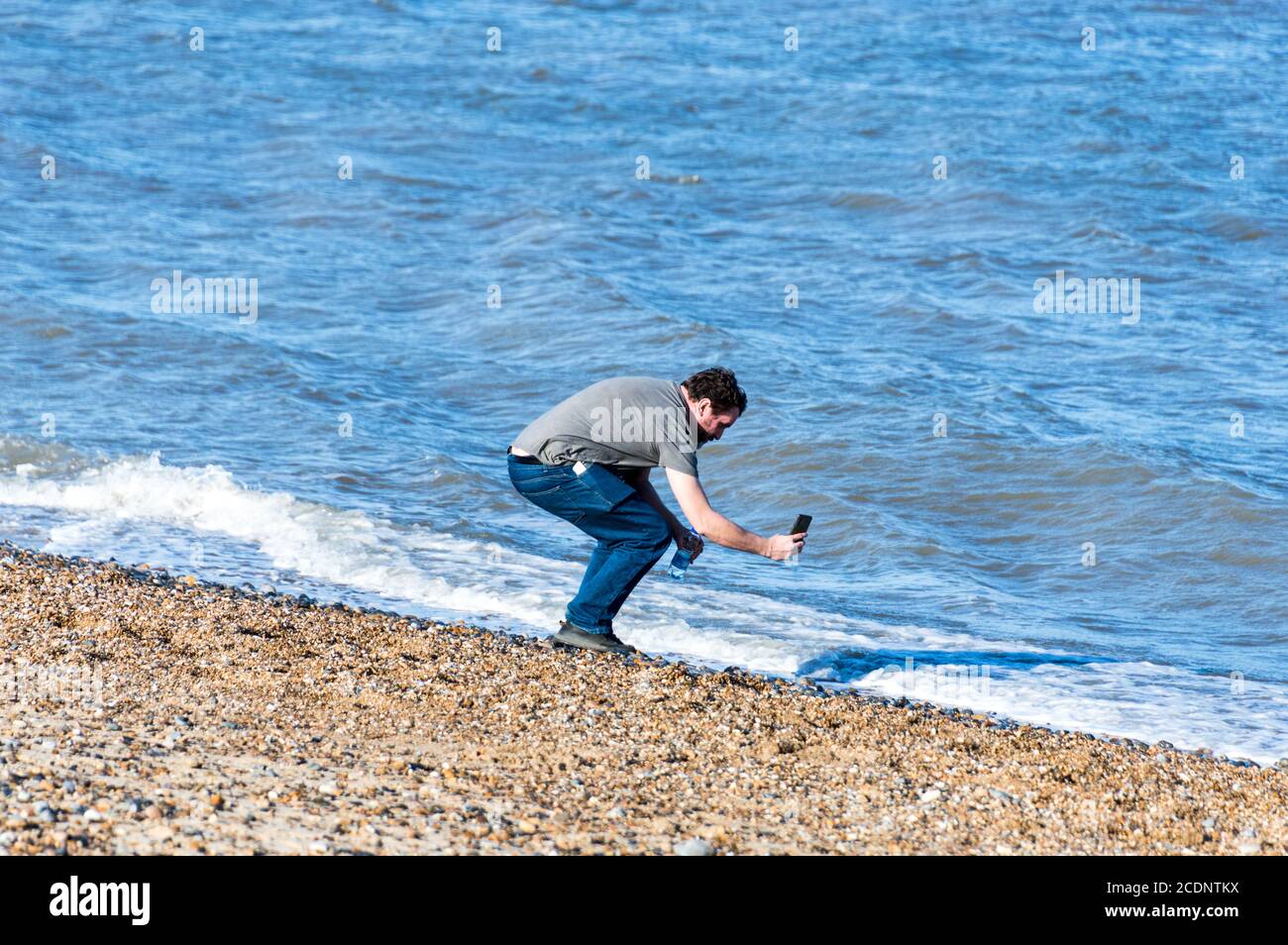 Mann, der mit einem Handy Wellen in Great Yarmouth, Norfolk, England fotografiert Stockfoto