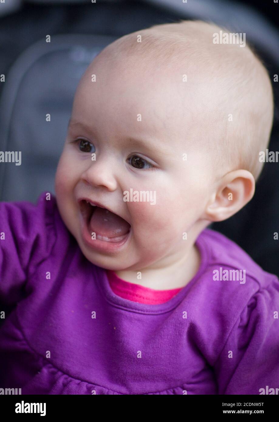 Ein glückliches Baby in lila Kleidung, sitzt in einem Kinderwagen Stockfoto