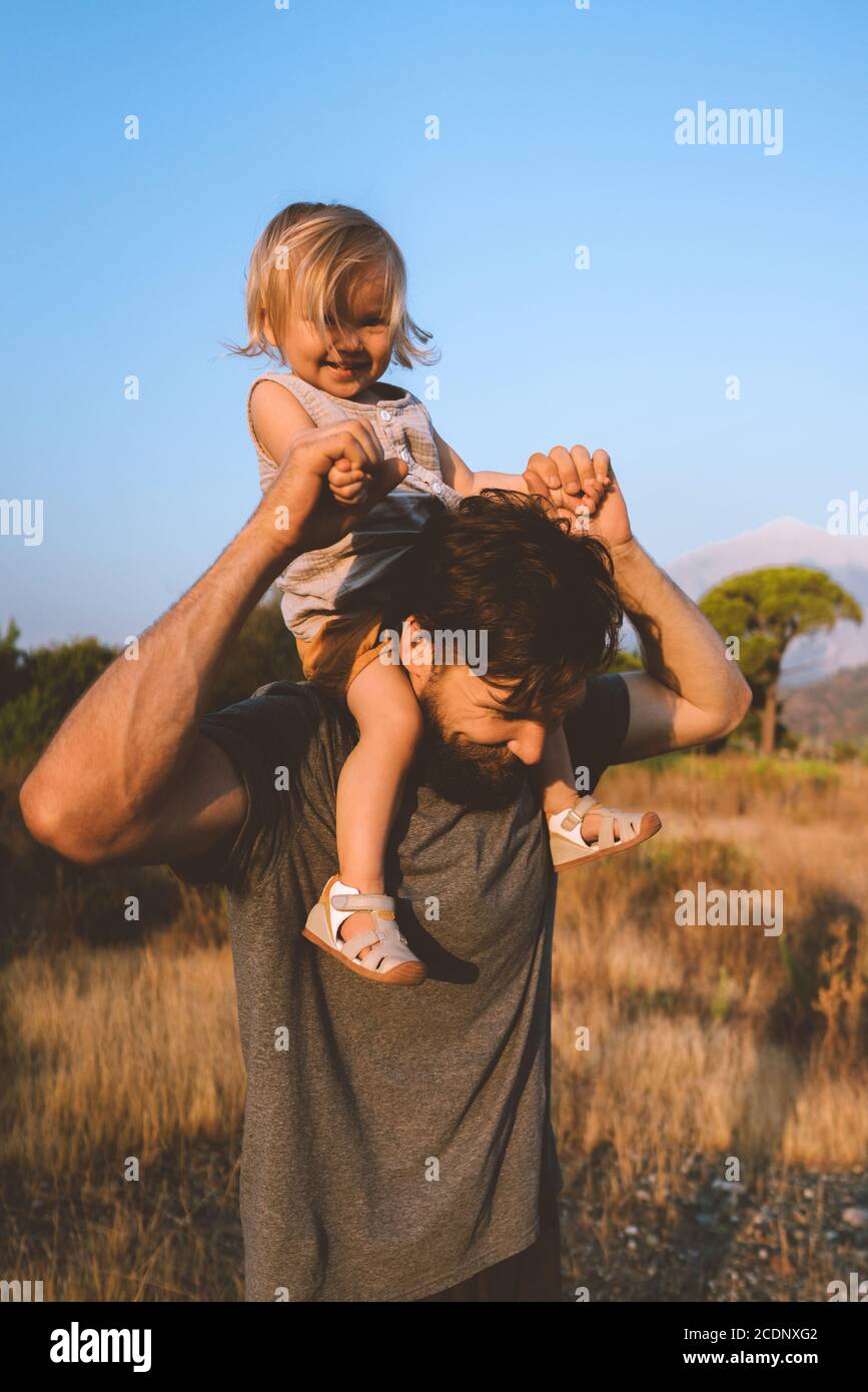 Kind Tochter sitzt auf Vater Schultern gehen im Freien Familie spielen Zusammen mit Spaß authentischen Lebensstil glückliche Emotionen Stockfoto