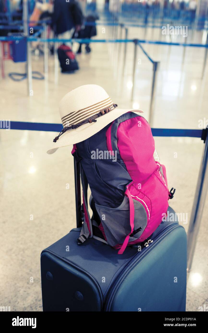Sommerhut, Rucksack und Koffer in der Flughafenhalle Stockfoto
