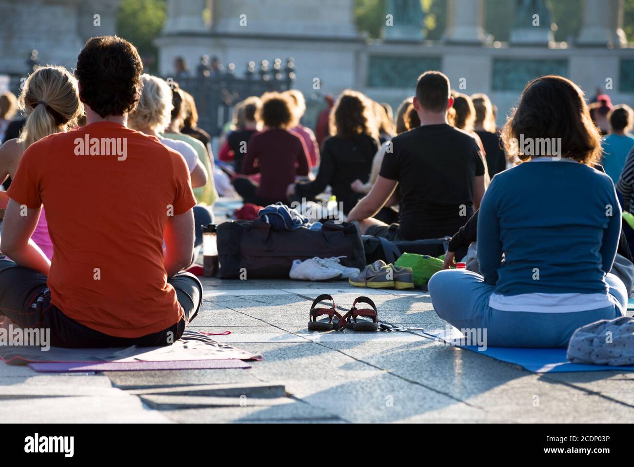 Gemischte Gruppe von Menschen, die im Freien in Lotusposition sitzen Stockfoto