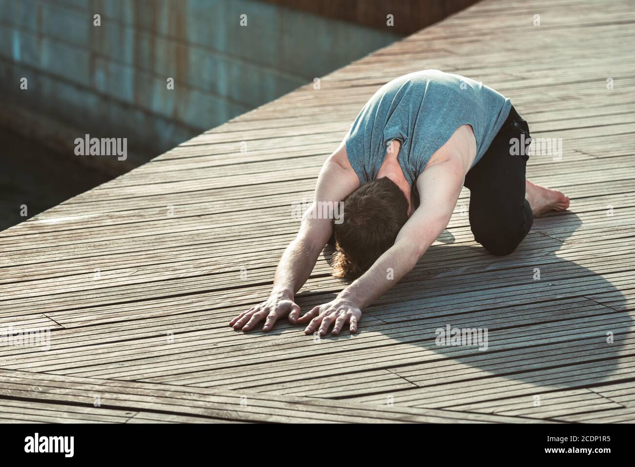 Balasana ist eine Yoga-Haltung, um Rückenschmerzen zu vermeiden, ein junger Mann übt sie. Stockfoto
