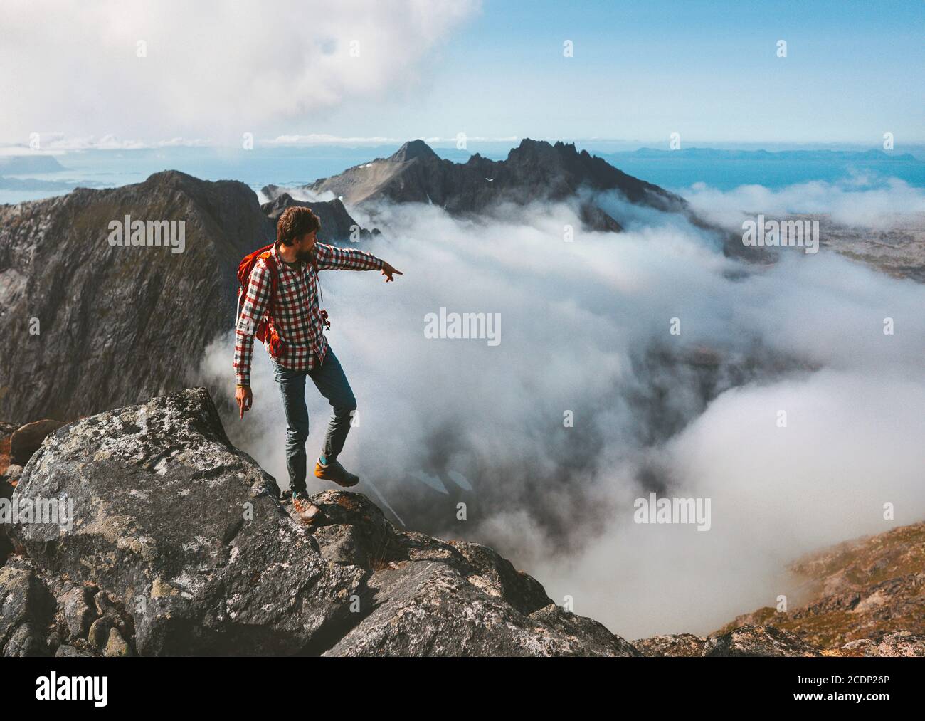 Mann unterwegs Wandern in den Bergen Outdoor-Aktivität Abenteuer Urlaub gesund Lifestyle-Wanderführer auf dem Gipfel über Wolken Hand zeigt Richtung ort Stockfoto