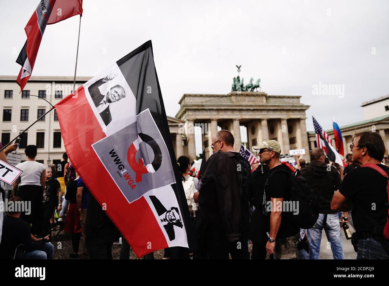 Berlin, Deutschland. August 2020. Auf einer schwarzen, weißen und roten Flagge, die ein Teilnehmer vor dem Brandenburger Tor hält, ist ein Bild von US-Präsident Donald Trump und der Buchstabe Q vor einer Demonstration gegen die Corona-Maßnahmen gedruckt. Quelle: Kay Nietfeld/dpa/Alamy Live News Stockfoto