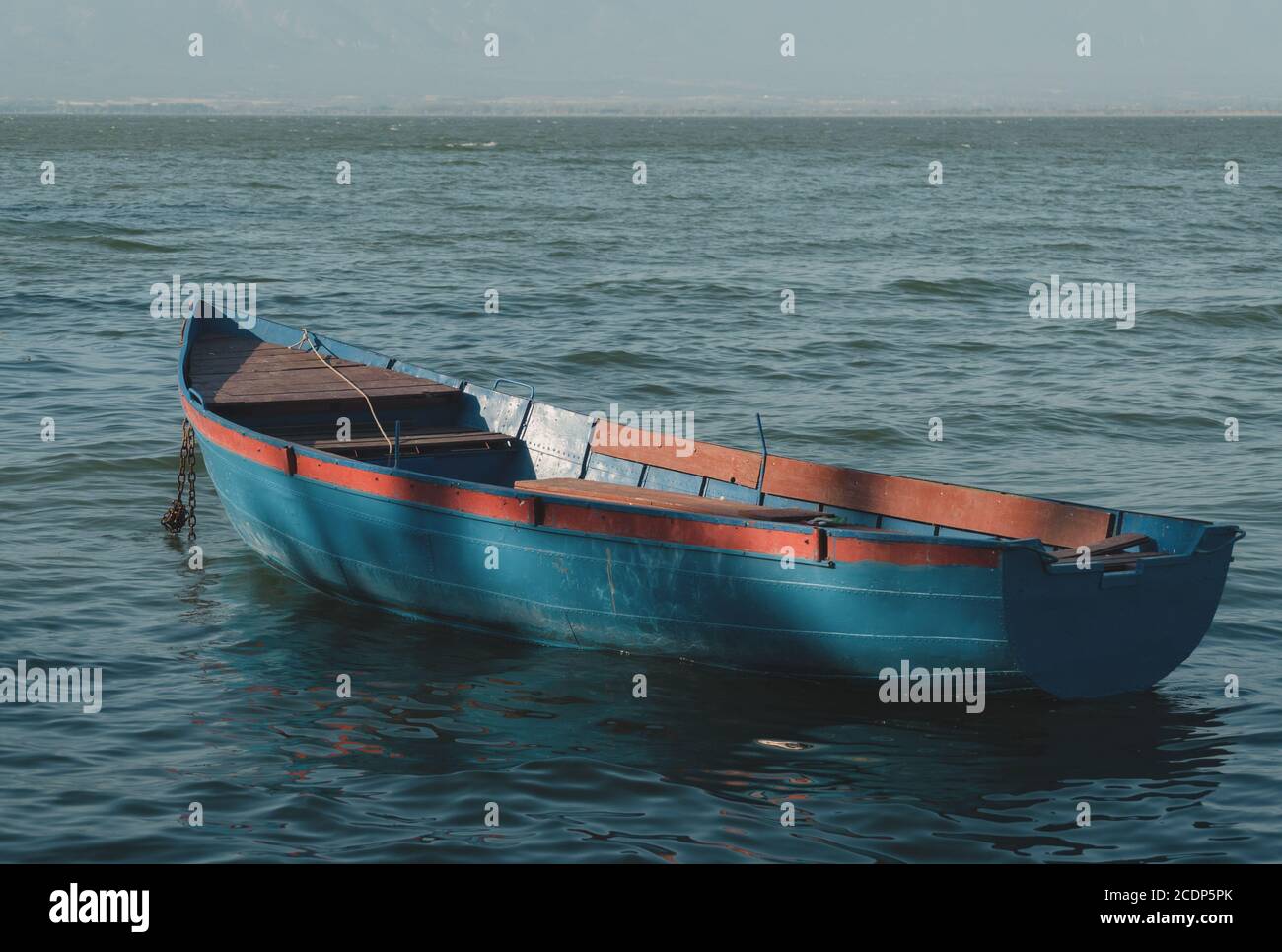 Kleines verankertes Fischerboot schwimmt im See Stockfoto