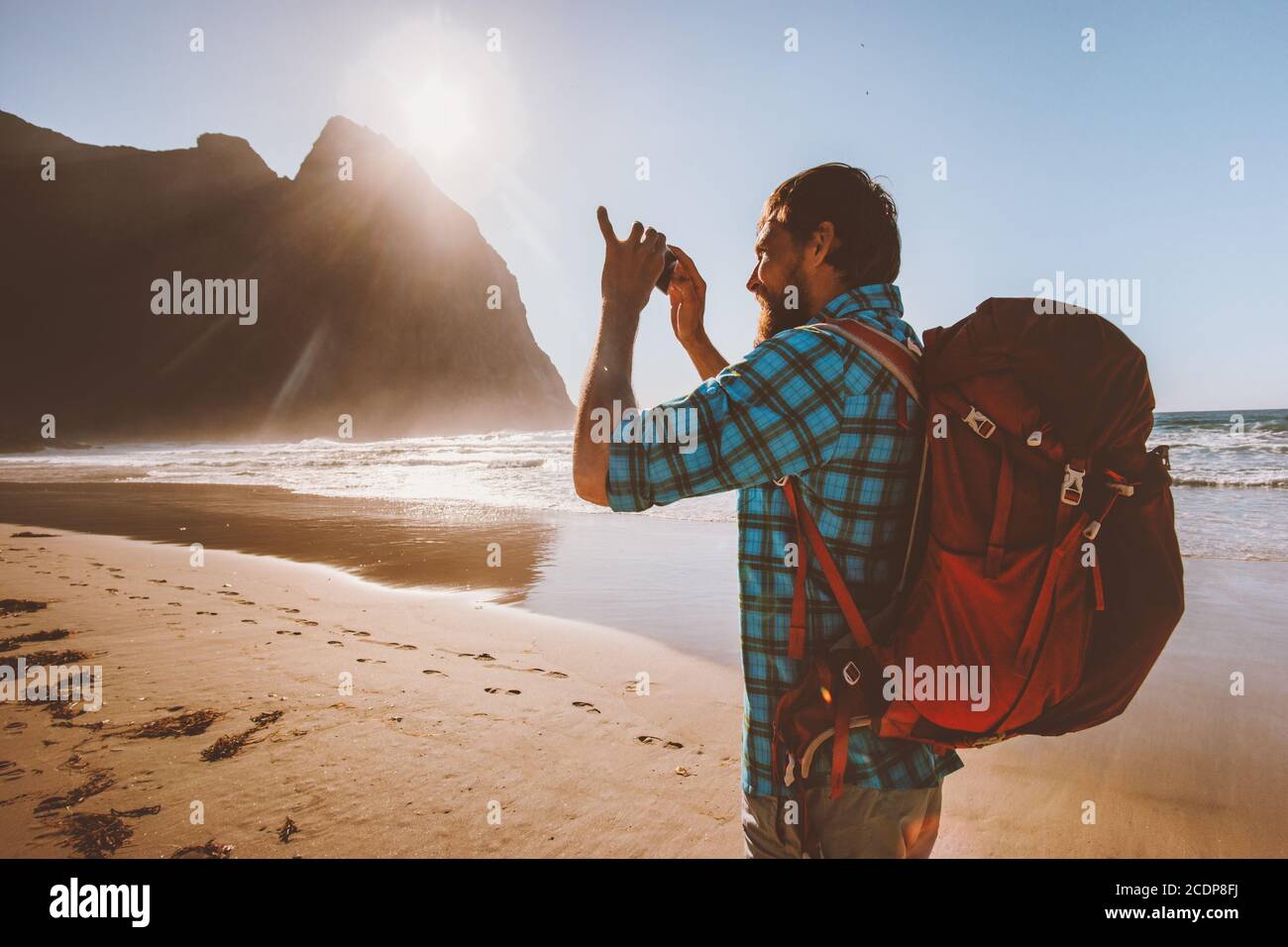 Mann Backpacker Foto mit Smartphone Kamera Reise Blogger Influencer In Norwegen Sommerurlaub Urlaub im Freien Kvalvika Strand Stockfoto