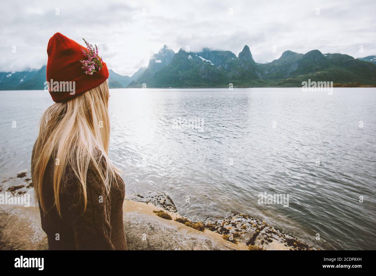 Frau allein in Norwegen Urlaub im Freien Sommer gesunde Lebensweise Blonde Haare Mädchen in roten Hut und Blumen genießen Aussicht Der Lofoten-Inseln Stockfoto