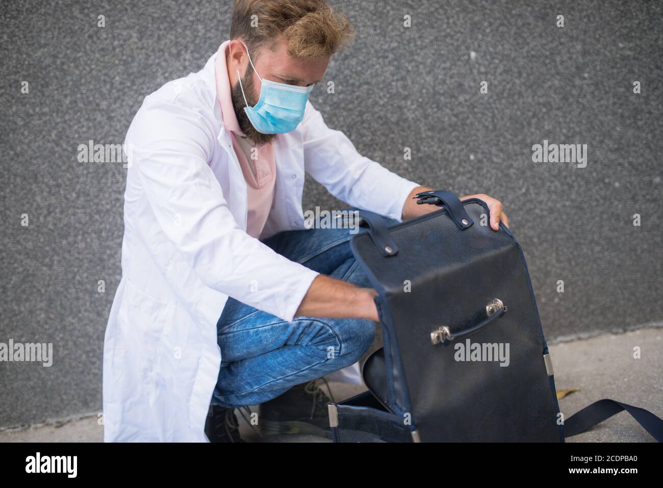 Junger Arzt, der eine Arzttasche trägt Stockfoto