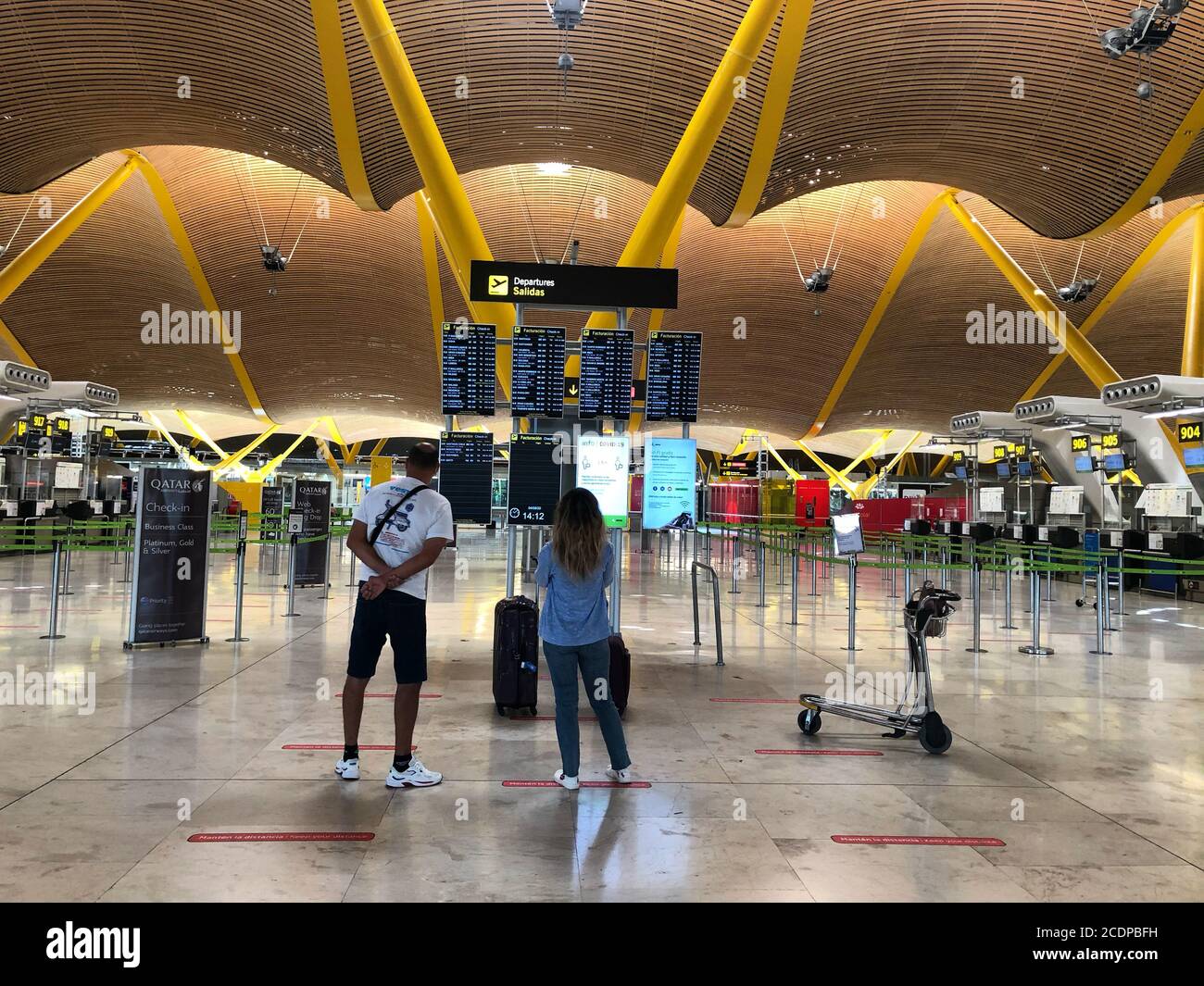 Zwei Touristen schauen sich im Sommer 2020 die Fluginformationsbildschirme am Flughafen Adolfo Suarez Madrid Barajas, Spanien an. Stockfoto