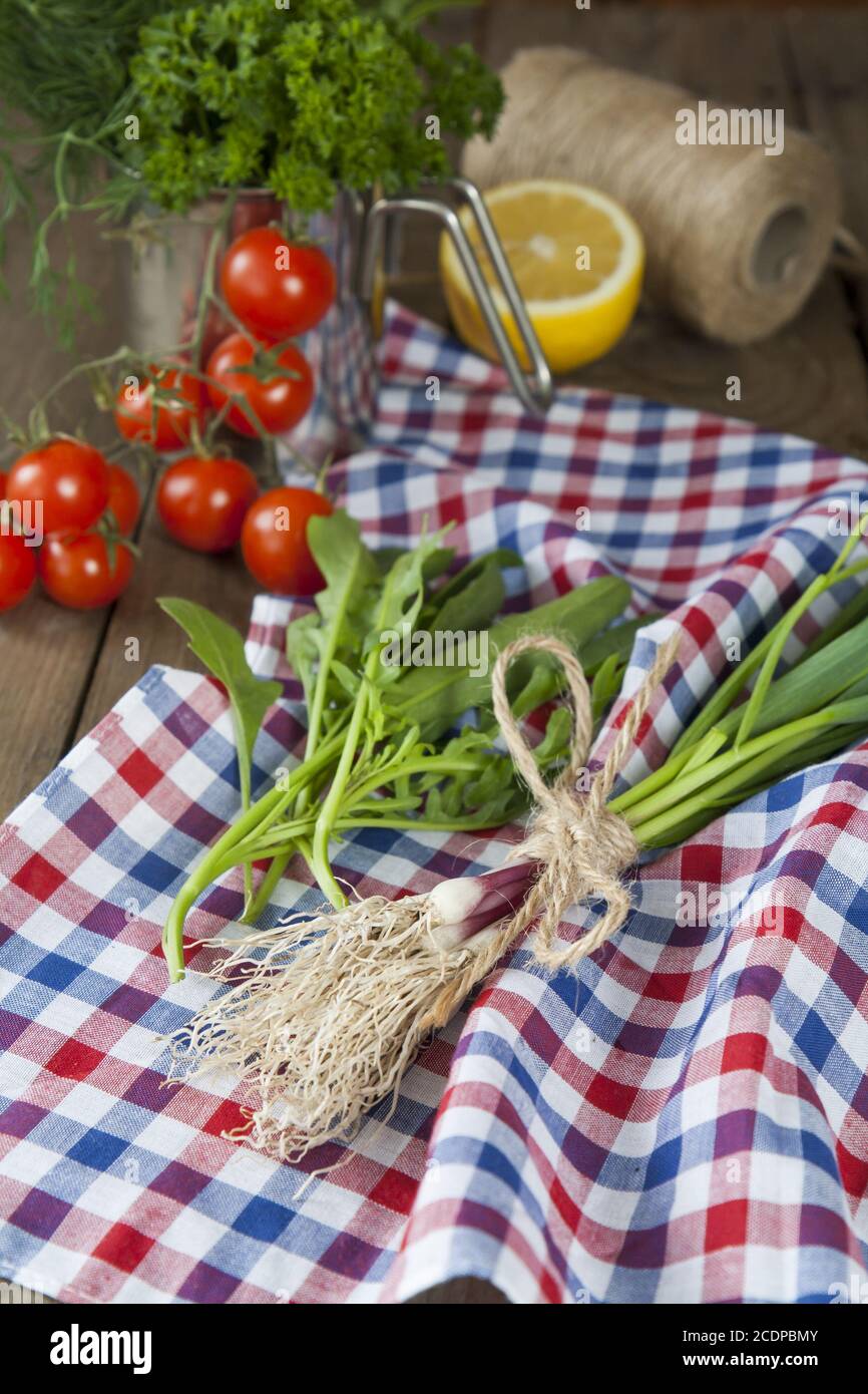 Frischer grüner Knoblauch Spears und Rucola auf Serviette mit Tomaten und Zitrone Stockfoto