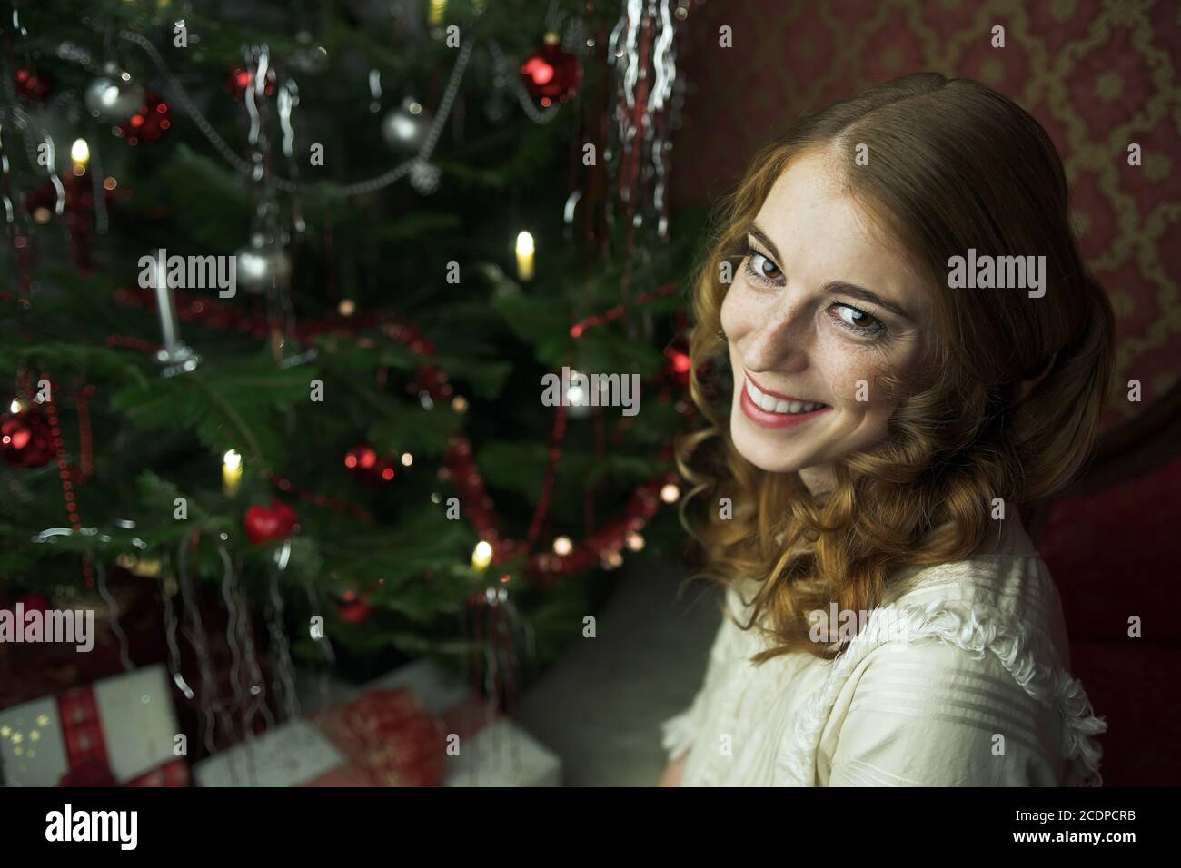 Viktorianische, historisch anmutende Weihnachtsszene mit einer jungen rothaarigen Frau in einem antiken Kleid Stockfoto