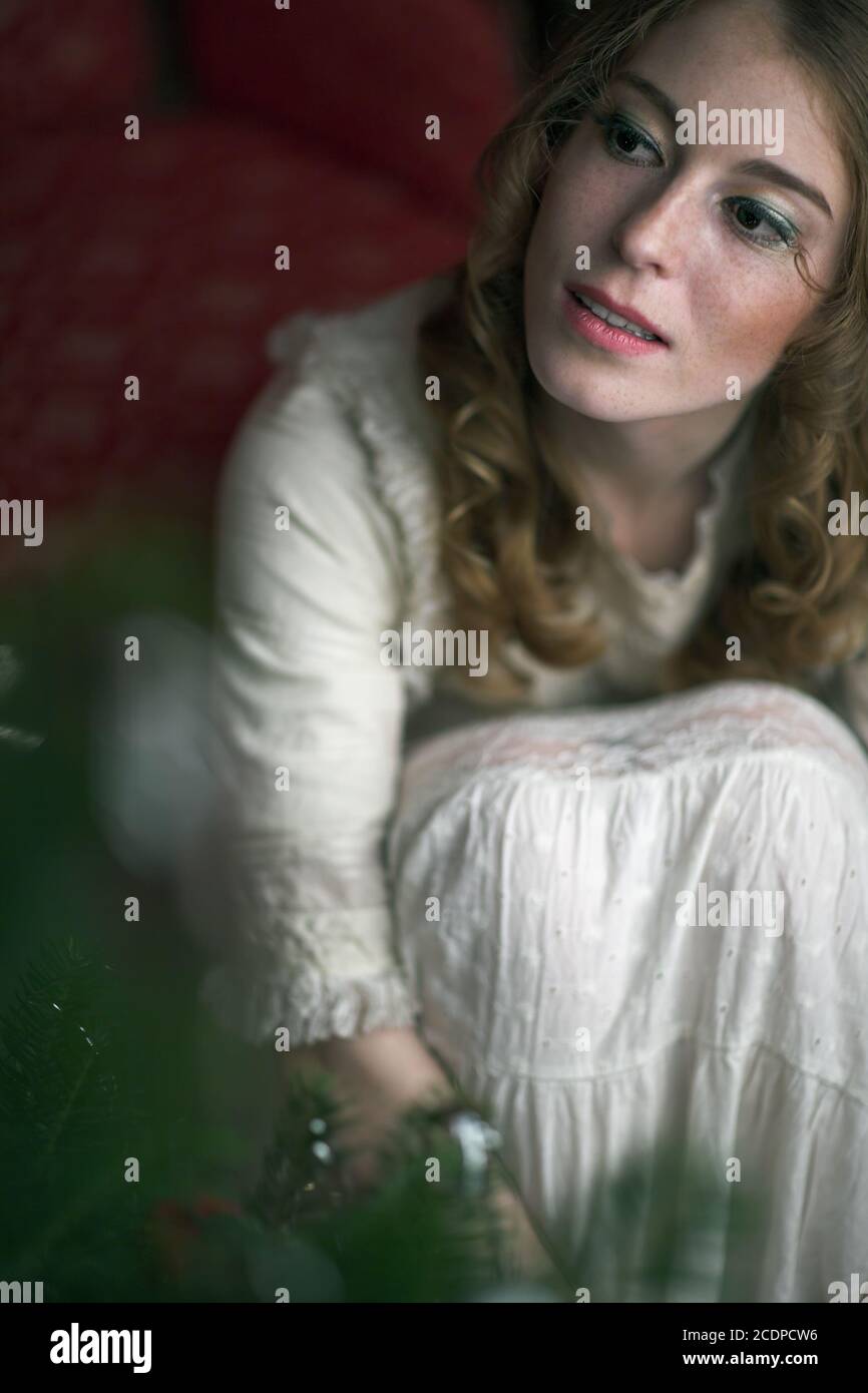 Viktorianische, historisch anmutende Weihnachtsszene mit einer jungen rothaarigen Frau in einem antiken Kleid Stockfoto