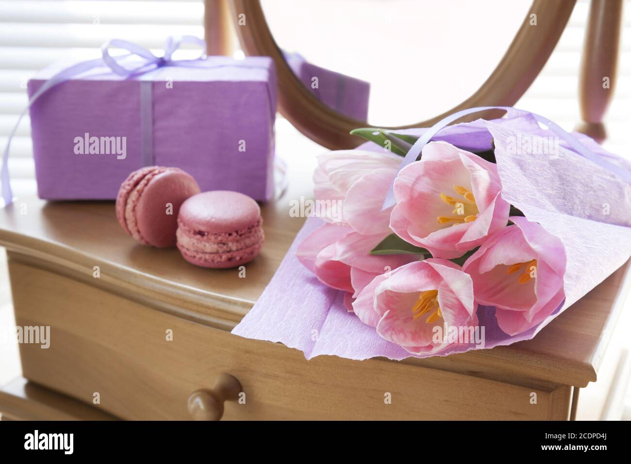 Rosa Tulpen in violetten Papier, zwei rosa Macarons, Geschenk und Spiegel, Hintergrundbeleuchtung, Hintergrund Stockfoto