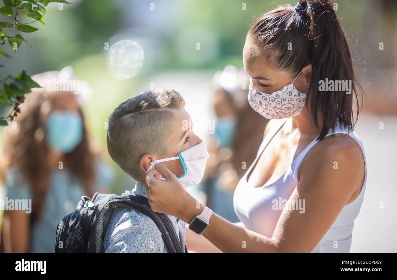 Eine Mutter und ihr Sohn verwenden eine Schutzmaske, wenn sie während der COVID-19-Quarantäne zur Schule zurückkehren. Stockfoto