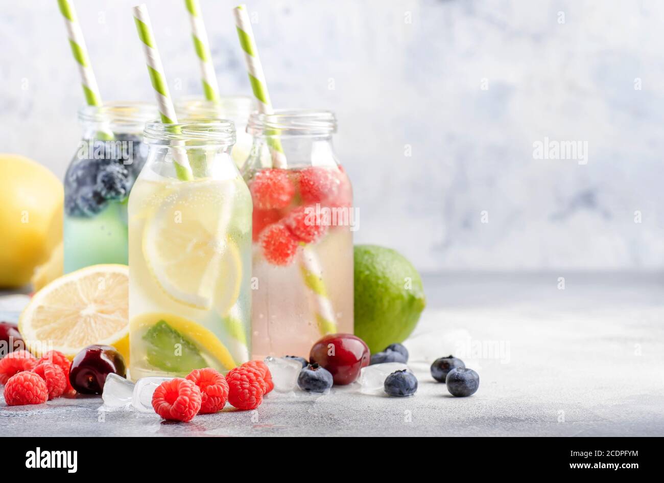 Beere und Zitrusfrüchte infundiert Sommer kalte Getränke in Glasflaschen auf grauen Stein Tisch Hintergrund, kopieren Raum Stockfoto