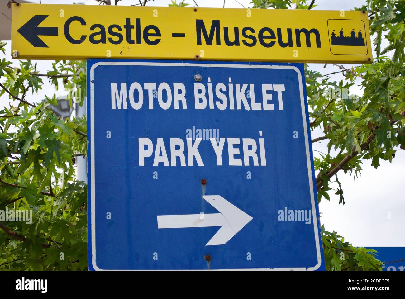 Zeiger auf das Schloss und Museum und die Übersetzung von blau-weißen Zeichen: 'Motorcycle Parkplatz'. Marmaris Türkei Stockfoto