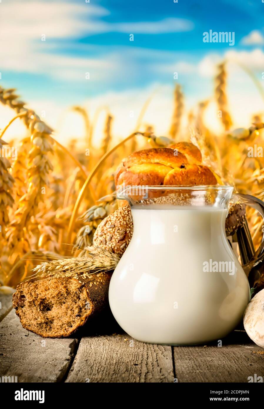 Milchprodukte und Brot auf Holztisch auf Feldhintergrund Stockfoto