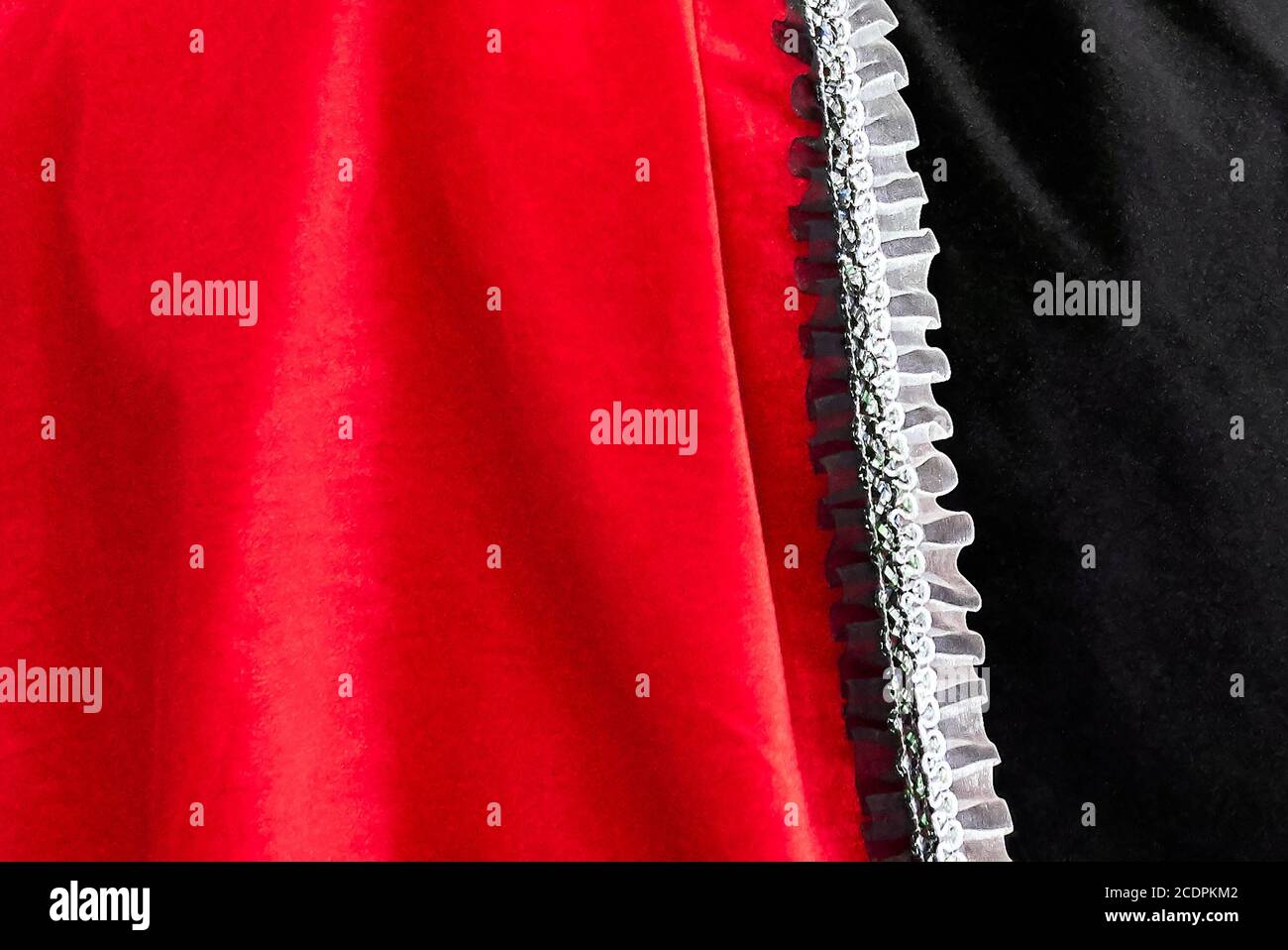 Nahaufnahme eines roten und schwarzen Stoffes mit aufgesetztem Stoff Weiße dekorative gewellte Bordüre Stockfoto