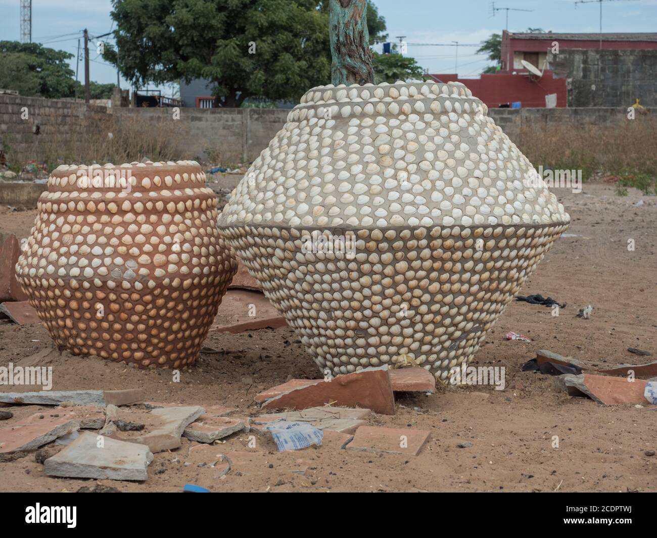 Zwei riesige, mit kleinen Muscheln bedeckte Vasen stehen auf einer Straße in Senegal, Westafrika. Stockfoto